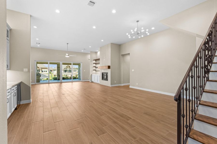 Elegant open-concept design featuring wood-look floors, designer lighting, and panoramic windows offering beautiful views of the outdoor living space.