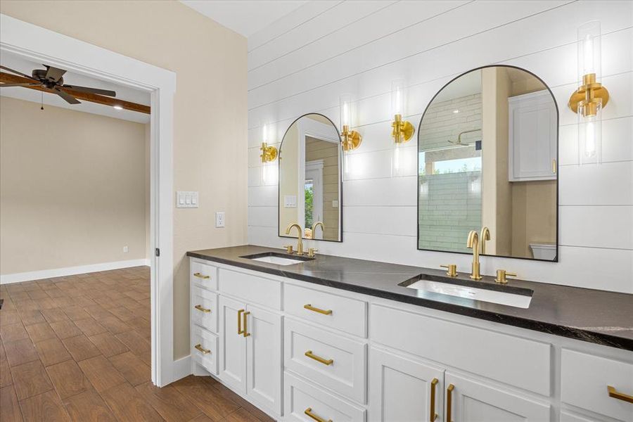 Full bath with double vanity, dark wood-style flooring, a tile shower, and ceiling fan Full bath with double vanity, dark wood-style flooring, a tile shower, and ceiling fan