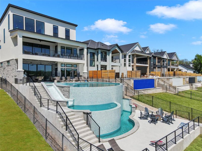 A multi-level custom pool overlooks the grassy backyard of this modern waterfront estate.