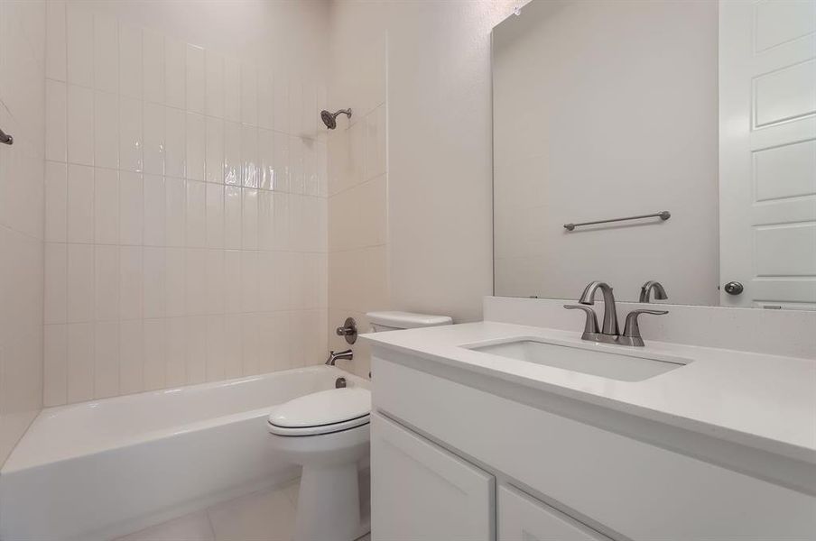 Full bathroom featuring tiled shower / bath, vanity, and toilet