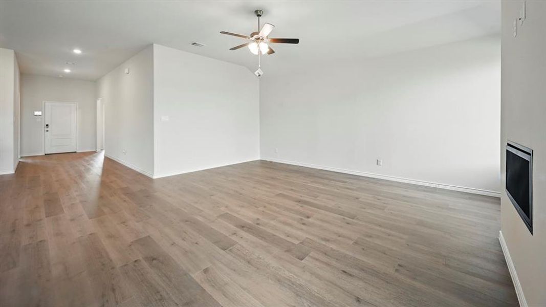 Unfurnished living room featuring light wood-style floors, a ceiling fan, and recessed lighting