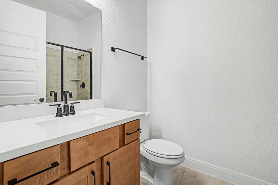 Bathroom featuring a textured wall, vanity, and a shower stall