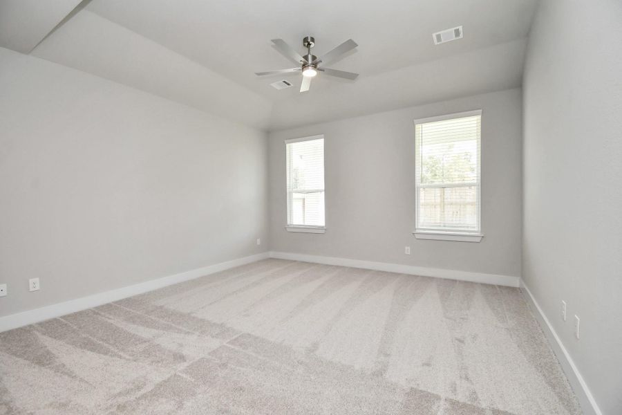 Come and unwind after a long day in this magnificent primary suite! This spacious room features plush carpet, warm paint, high ceilings and large windows with privacy blinds. Sample photo of completed home with similar floor plan. Actual colors and selections may vary.