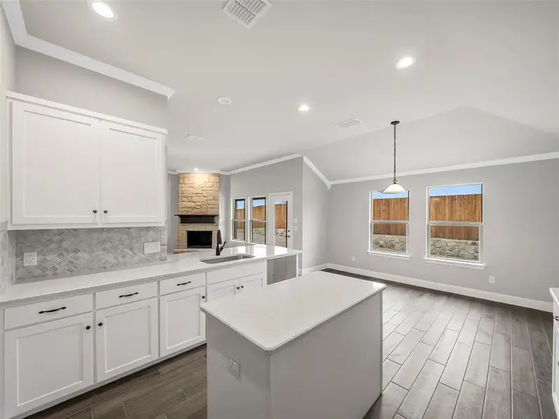 Kitchen featuring visible vents, crown molding, open floor plan, and a sink