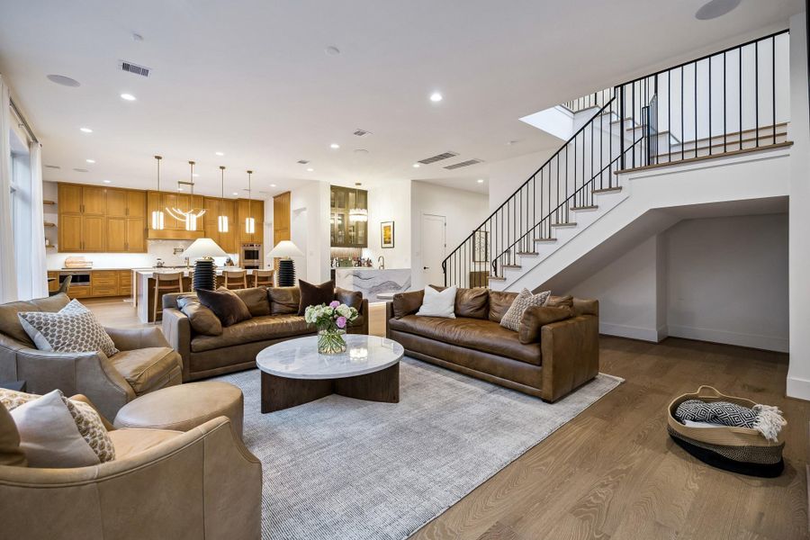 Another view of the den, open to the kitchen, highlights the home’s stunning staircase as a beautiful focal point.