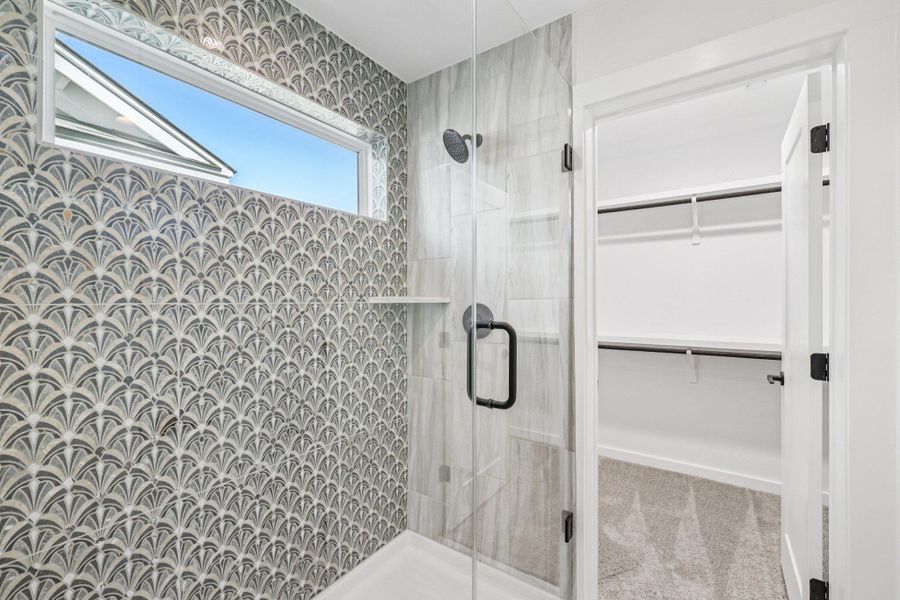 Full bathroom with a spacious closet and a shower stall