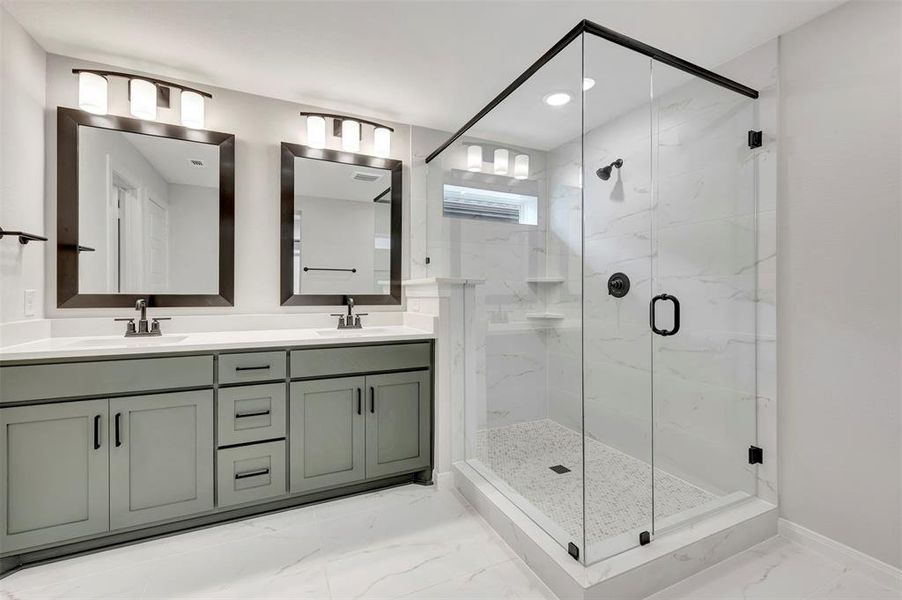 Full bath with double vanity, light marble finish flooring, a marble finish shower, and recessed lighting