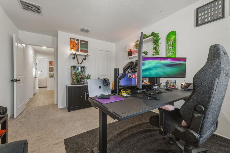 This room features light-colored walls, carpeted flooring, and a doorway leading to an additional interior space