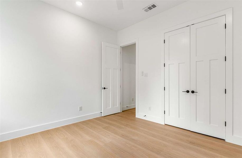 Unfurnished bedroom with light wood-style flooring, a closet, and a ceiling fan