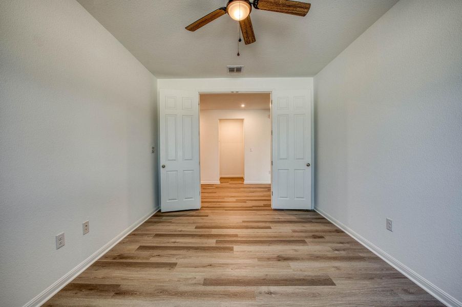 Double doors open to reveal versatile space finished with handsome wood-look flooring.