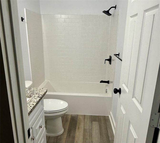 Bathroom with bathing tub / shower combination, dark wood finished floors, and vanity