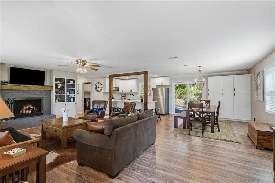 Expansive living area featuring wood-finish flooring, a painted brick fireplace with a wood mantle, and a built-in display cabinet