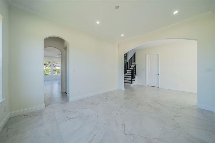 Empty room with arched walkways, light marble finish floors, recessed lighting, stairway, and ornamental molding Empty room with arched walkways, light marble finish floors, recessed lighting, stairway, and ornamental molding