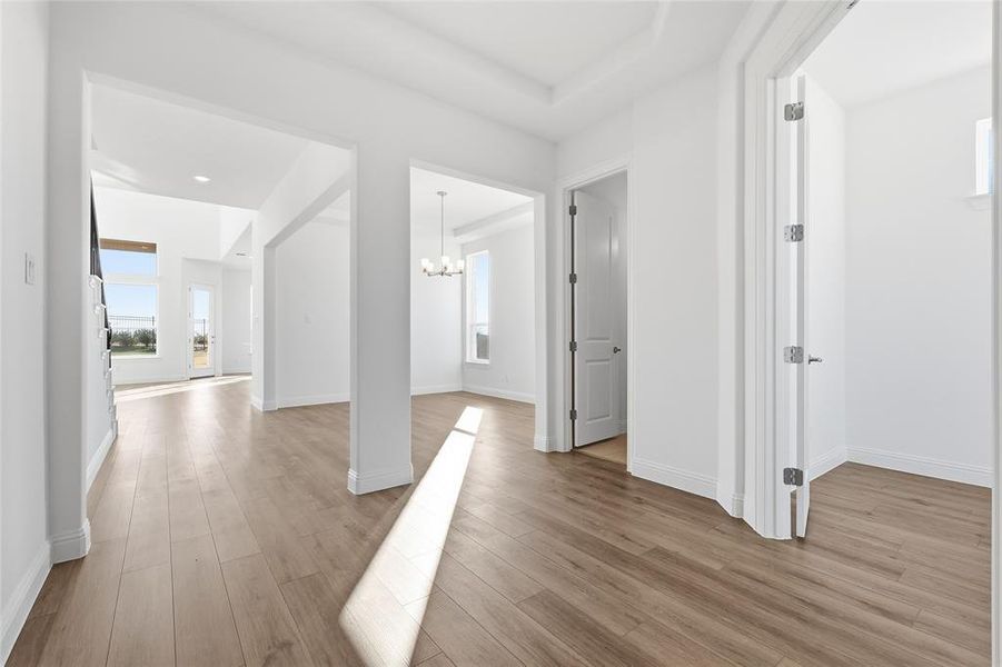 Hallway with suspended lighting and light wood-style floors Hallway with suspended lighting and light wood-style floors