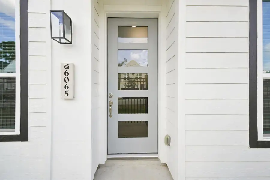Modern front entry featuring a contemporary glass-panel door, clean architectural details, and exterior lighting. Modern front entry featuring a contemporary glass-panel door, clean architectural details, and exterior lighting.