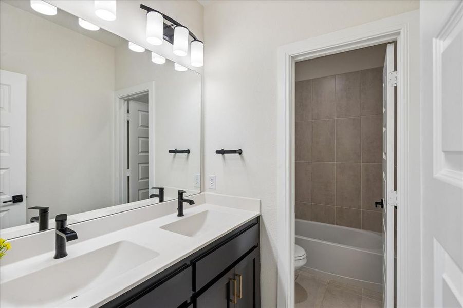 Bathroom featuring a dual vanity with flat-panel cabinetry, white countertops, and matte black fixtures Bathroom featuring a dual vanity with flat-panel cabinetry, white countertops, and matte black fixtures