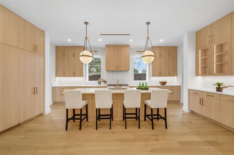 Kitchen featuring a breakfast bar, modern cabinets, pendant lighting, light brown cabinetry, and recessed lighting
