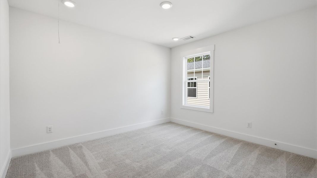 Accomplished design in this restful bedroom featuring plush carpet and oversized window views at Iris Meadows