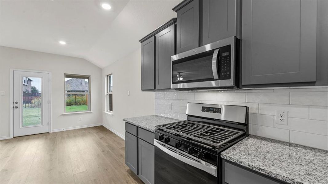 Kitchen featuring stainless steel appliances, grey cabinetry, and light-toned countertops