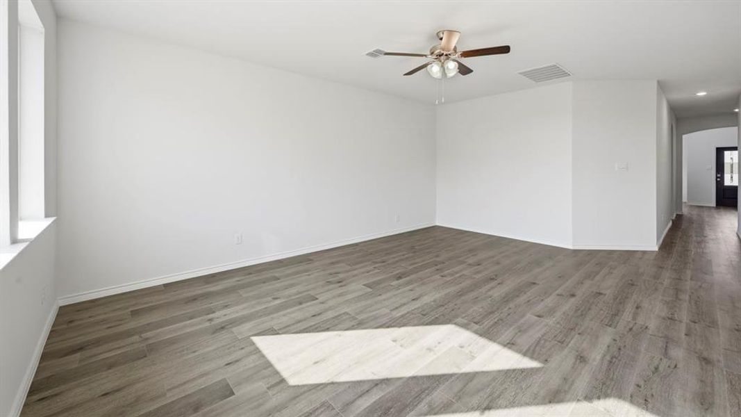 Spacious interior featuring wood-finish flooring, white baseboards, and a ceiling fan with integrated lighting Spacious interior featuring wood-finish flooring, white baseboards, and a ceiling fan with integrated lighting