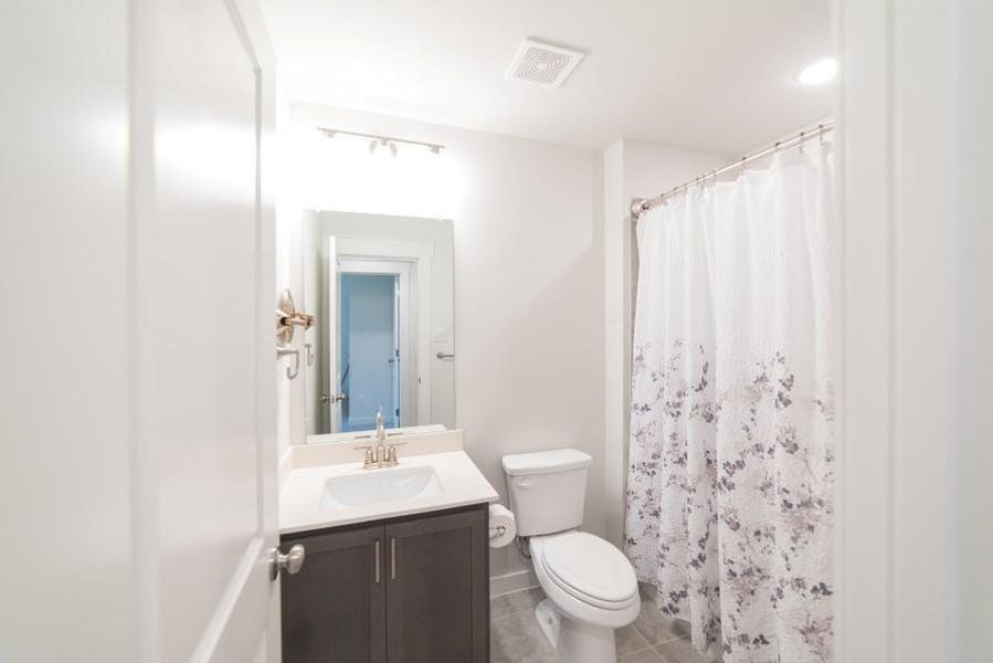 Bathroom with curtained shower, vanity, and light tile patterned flooring