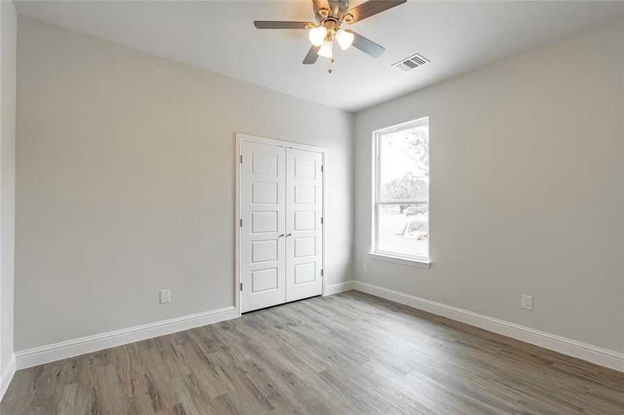 Unfurnished bedroom with multiple windows, ceiling fan, a closet, and light hardwood / wood-style flooring