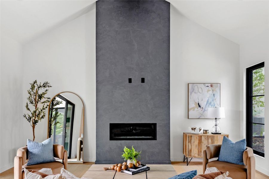 Living area featuring high vaulted ceiling, a glass covered fireplace, and wood finished floors