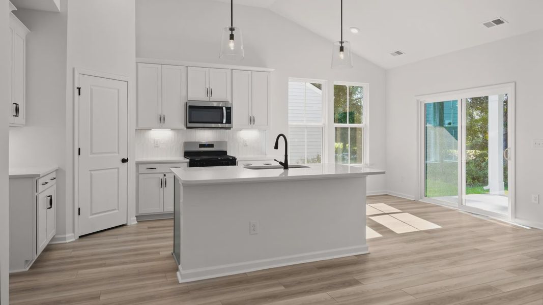 A chef’s kitchen with quartz countertops, a large island, and walk-in pantry
