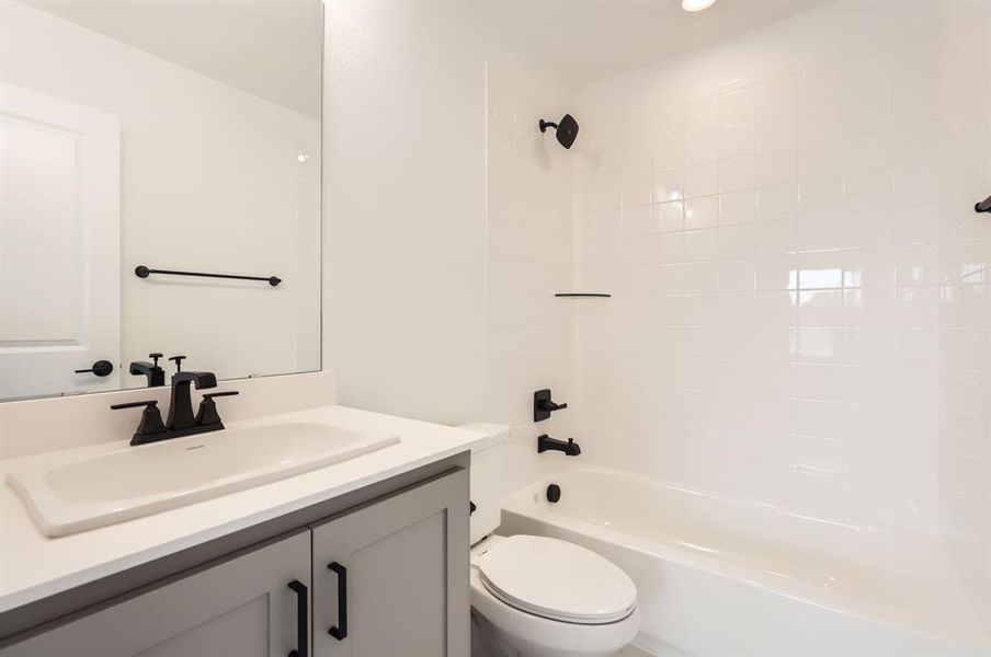 Full bathroom with toilet, tiled shower / bath combo, and vanity