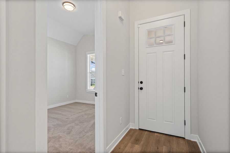 Entryway featuring a paneled door with frosted glass inserts, matte black hardware, and wood-finish flooring Entryway featuring a paneled door with frosted glass inserts, matte black hardware, and wood-finish flooring