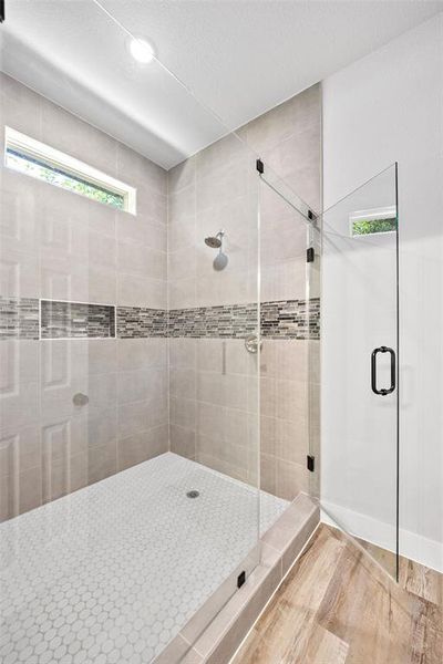 Full bath featuring a shower stall, wood finished floors, and a textured ceiling