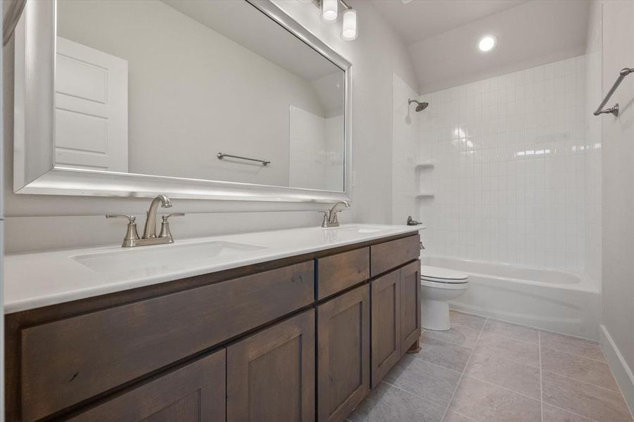 Full bath featuring double vanity, shower / washtub combination, light tile patterned flooring, and recessed lighting