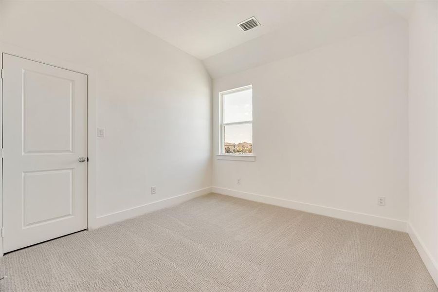 Unfurnished room with light carpet and lofted ceiling Unfurnished room with light carpet and lofted ceiling