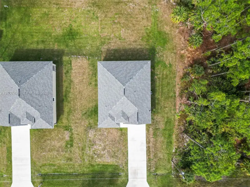 Aerial perspective featuring expansive grass lots, asphalt shingle rooflines, concrete driveways, and mature pine tree borders Aerial perspective featuring expansive grass lots, asphalt shingle rooflines, concrete driveways, and mature pine tree borders