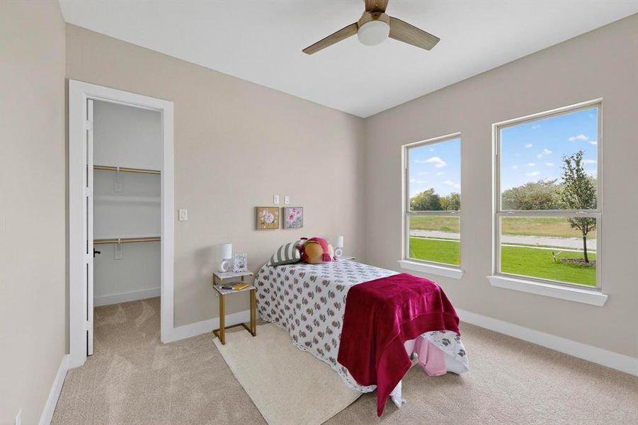Bedroom featuring light carpet, a walk in closet, and ceiling fan
