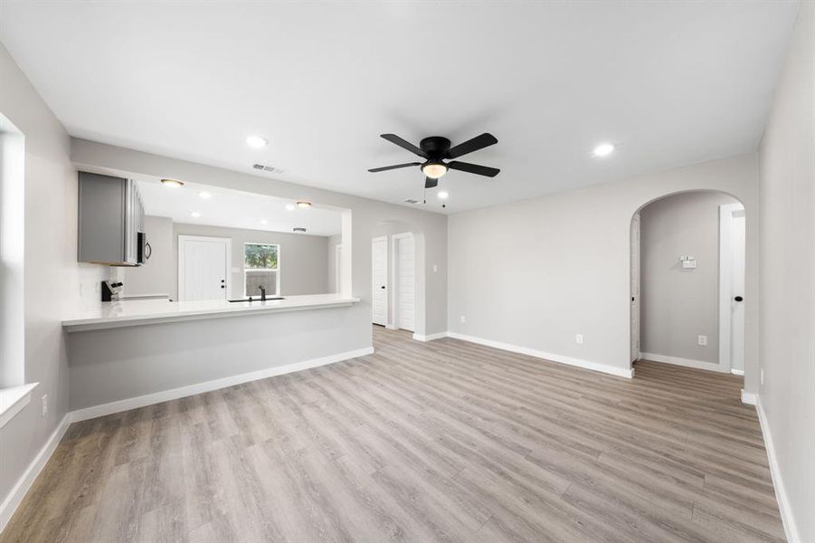 Unfurnished living room with arched walkways, recessed lighting, light wood-type flooring, and ceiling fan Unfurnished living room with arched walkways, recessed lighting, light wood-type flooring, and ceiling fan