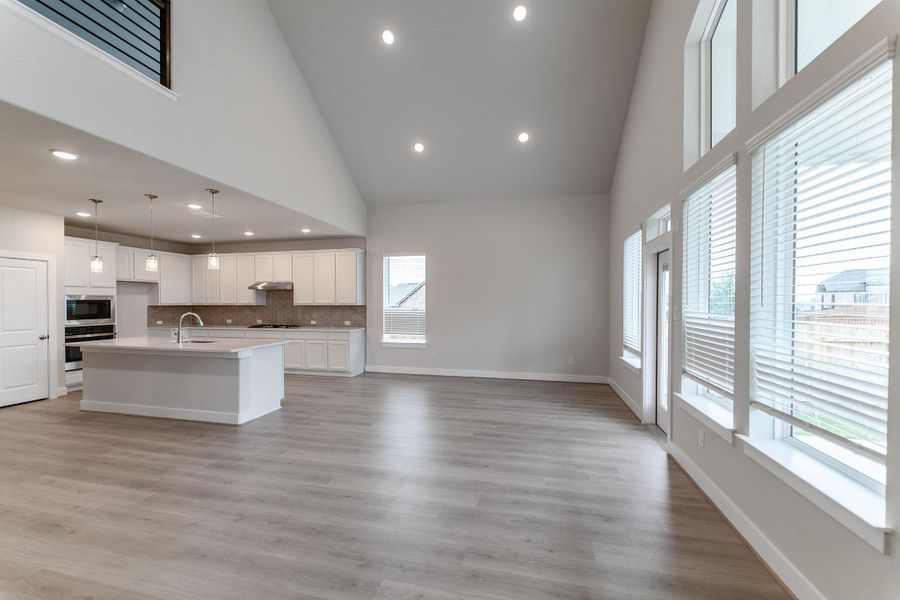 Kitchen featuring white cabinets, open floor plan, vaulted ceiling, a center island with sink, and tasteful backsplash