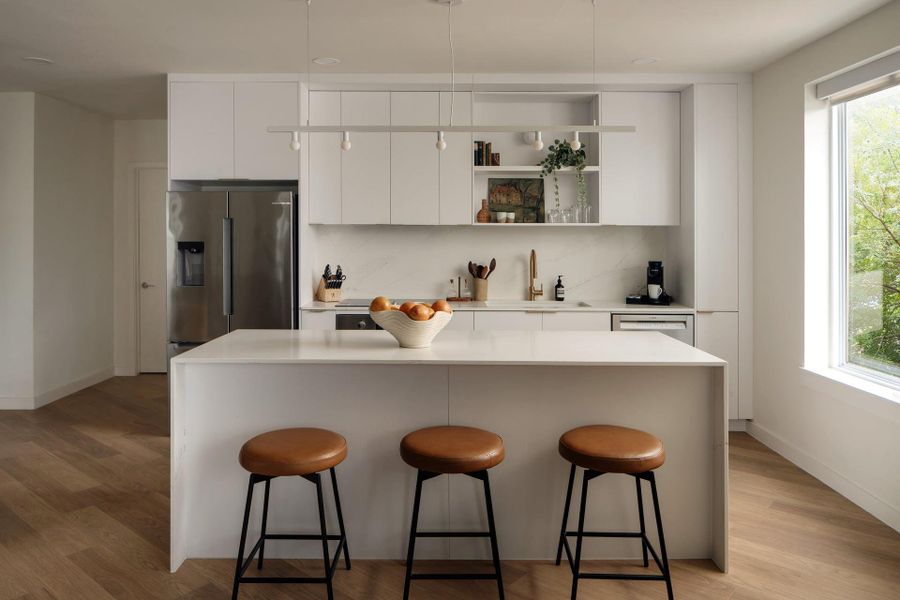 A spacious kitchen island with solid stone countertops serves as the focal point. A spacious kitchen island with solid stone countertops serves as the focal point.