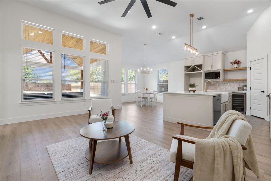 Living room featuring wine cooler, light wood finished floors, recessed lighting, a ceiling fan, and a chandelier Living room featuring wine cooler, light wood finished floors, recessed lighting, a ceiling fan, and a chandelier