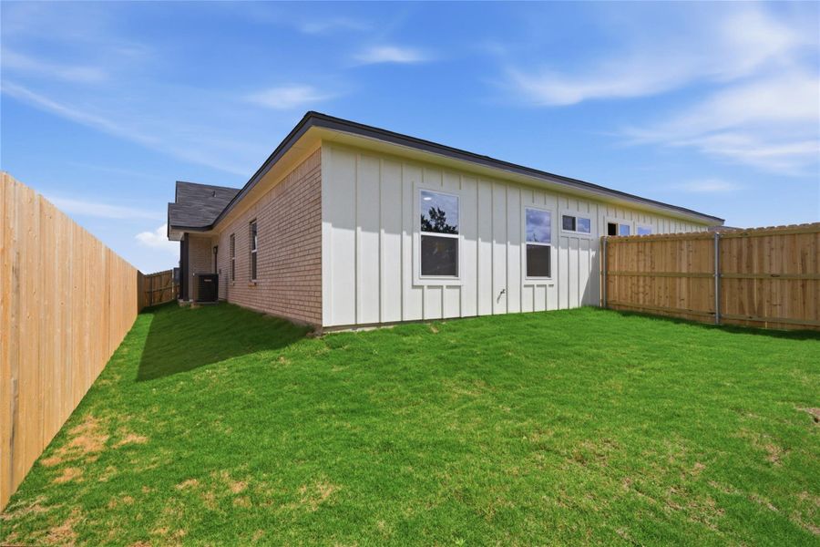 Back of property with brick siding, a fenced backyard, and board and batten siding