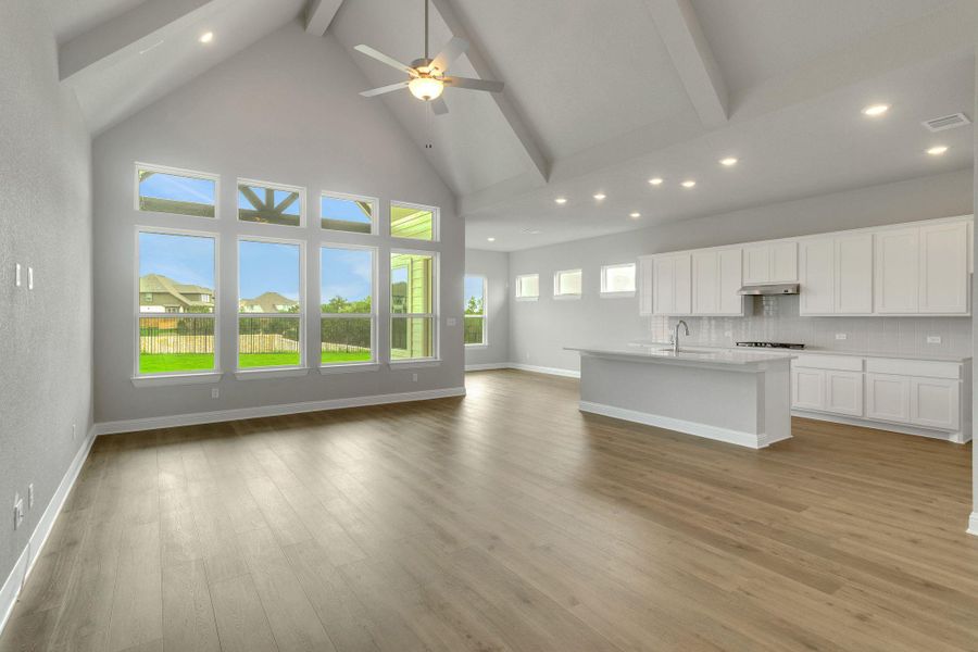 Unfurnished living room with beam ceiling, high vaulted ceiling, recessed lighting, light wood-type flooring, and a sink