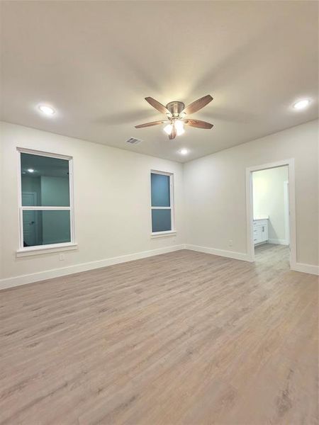 Master/ primary bedroom with luxury vinyl flooring, picture of ensuite bathroom, plenty of lightning and ceiling fan.