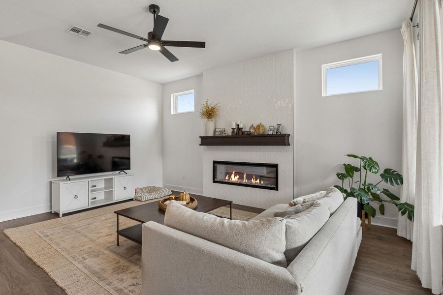 A modern fireplace with a dark mantel anchors this airy living space with wood flooring.