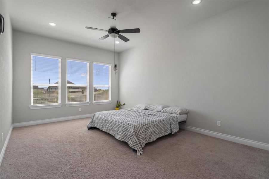 High ceilings and tall windows enhance the natural light in this carpeted bedroom.