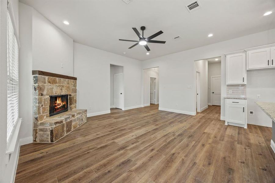 Unfurnished living room with a stone fireplace, light wood-style flooring, a ceiling fan, and recessed lighting Unfurnished living room with a stone fireplace, light wood-style flooring, a ceiling fan, and recessed lighting