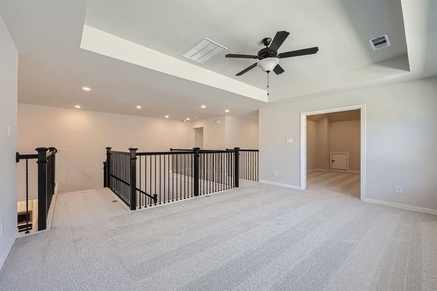 Carpeted spare room featuring ceiling fan and a raised ceiling