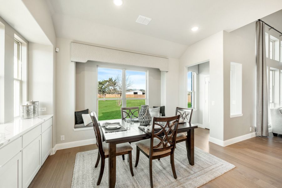Dining area with dark wood table, built-in window seat, and large windows overlooking a backyard Dining area with dark wood table, built-in window seat, and large windows overlooking a backyard