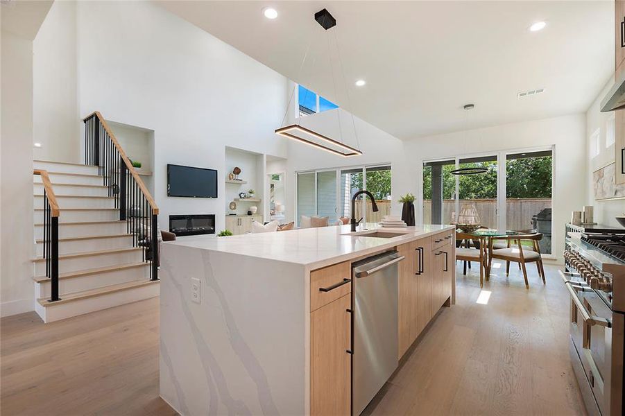 Kitchen with light hardwood / wood-style flooring, stainless steel appliances, a center island with sink, sink, and light brown cabinetry