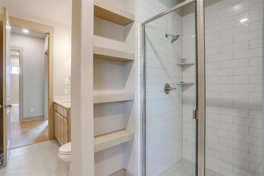 Full bath featuring tile patterned floors, built in features, toilet, vanity, and a stall shower