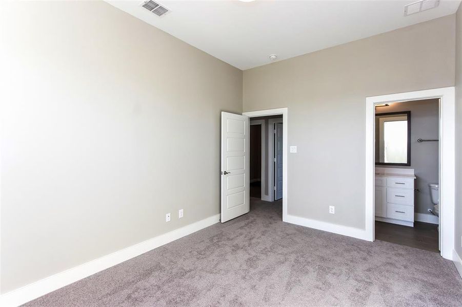 Unfurnished bedroom featuring ensuite bathroom and light colored carpet